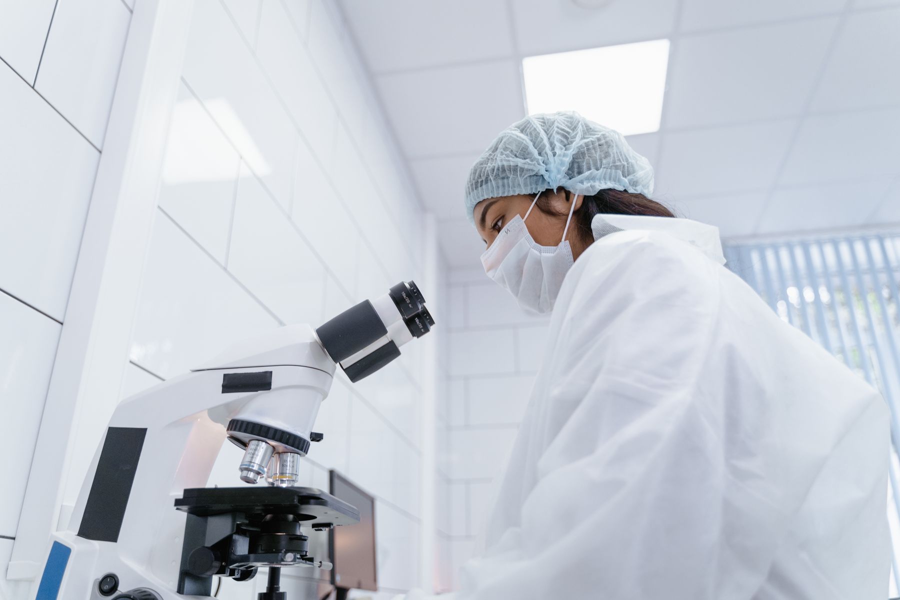 Chercheuse utilisant un microscope dans un laboratoire de recherche.